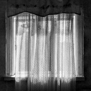 A monochrome image of a window adorned with curtains