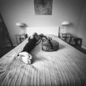 Musician relaxing on bed with cello