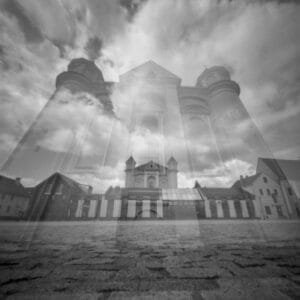 Double exposure of a black and white church against a sky backdrop