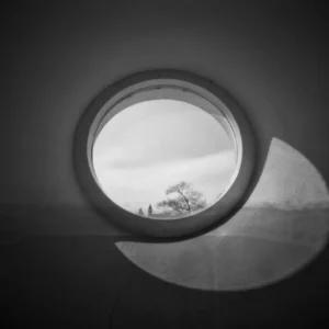 A monochrome image of a round window, showcasing contrasting shades of black and white